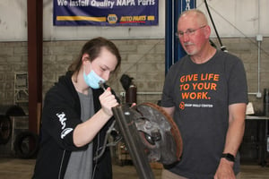 A student and mentor work together on a brake assembly in the Equip Skills Center garage.